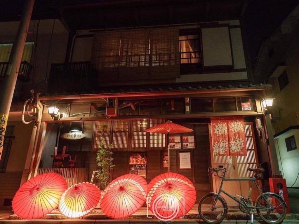 京都Guesthouse HANA Nishijin的一群红色的雨伞,在一座建筑前