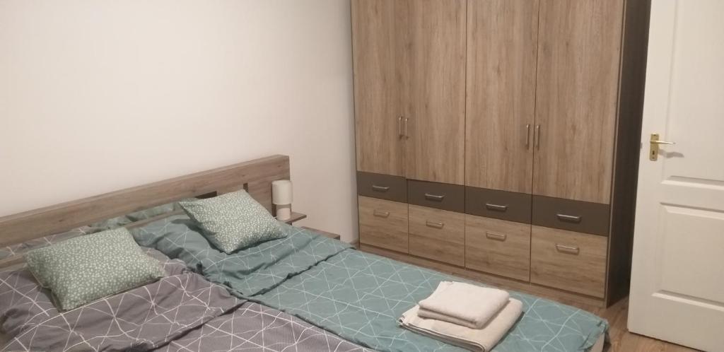 KomlóJószerencsét apartman的一间卧室配有一张床和一个木制橱柜