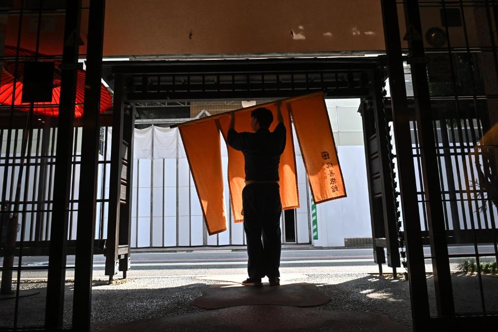 京都棉善酒店的站在带旗帜的大门上的男人
