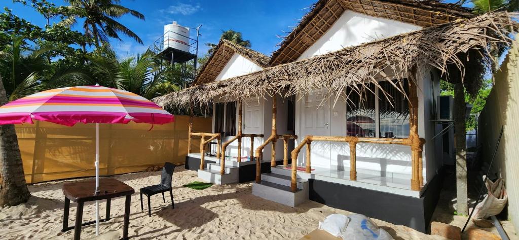阿勒皮Bliss Beach Villa的海滩上带桌子和遮阳伞的房子