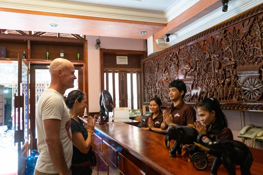 金边Nawin Palace Guesthouse的一群人站在酒吧周围