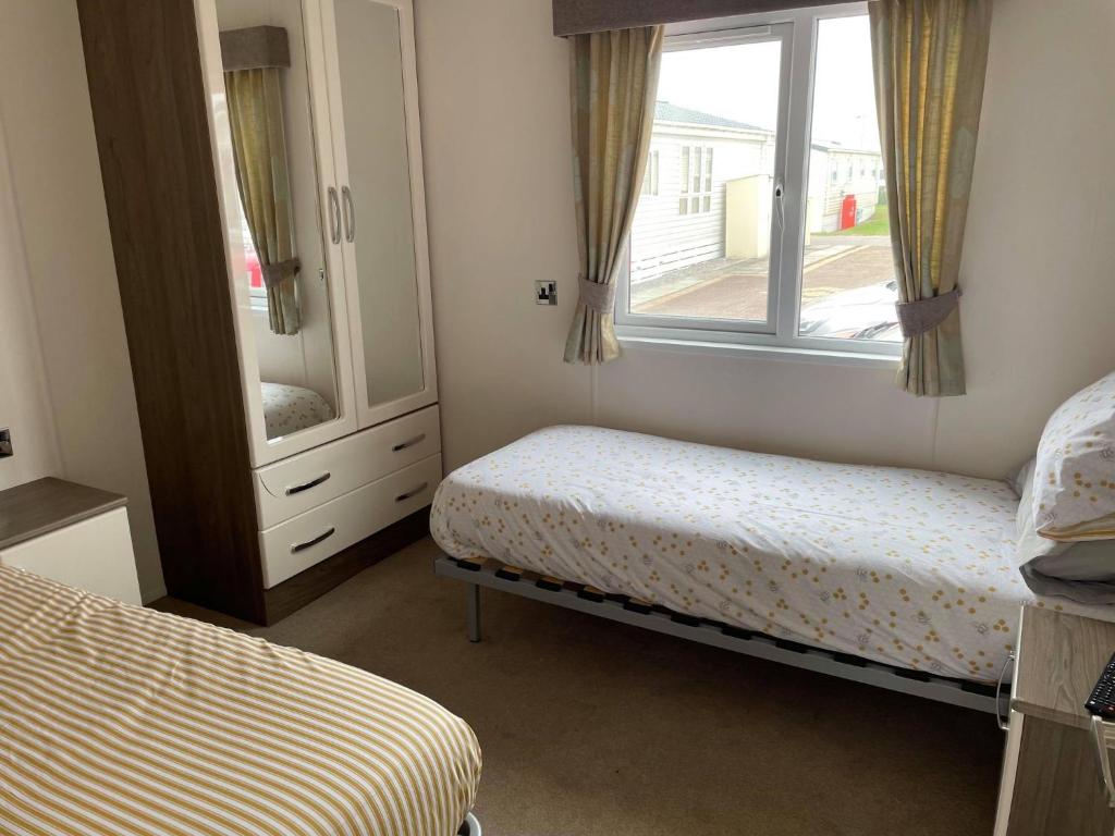 纽顿2 Bedroom Lodge - Honeysuckle 95, Trecco Bay的一间卧室设有两张床、镜子和窗户