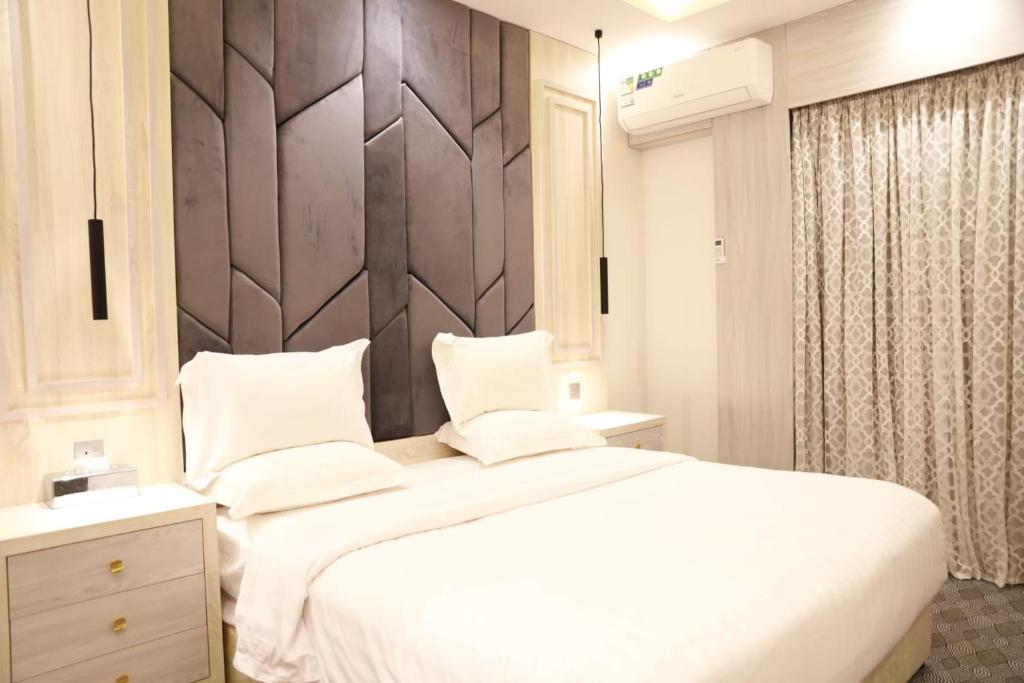 艾卜哈فندق المساء的卧室配有白色的床和木制床头板