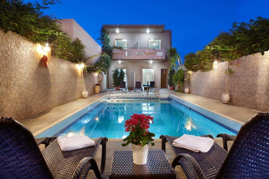 加藤-达拉特索太阳尼古拉斯公寓式酒店的一个带椅子和桌子的游泳池以及一座房子