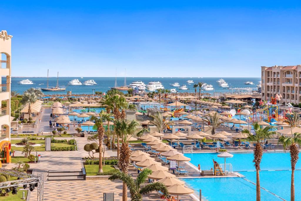 赫尔格达Pickalbatros White Beach Resort - Hurghada的享有带游泳池和遮阳伞的度假村景色