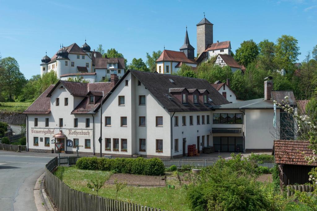 奥夫塞斯Brauereigasthof Rothenbach的一座白色的房子,后面有一座村庄