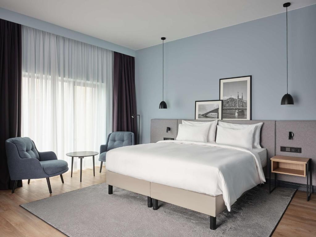 布达佩斯Radisson Hotel Budapest BudaPart的卧室配有一张白色大床和一把椅子