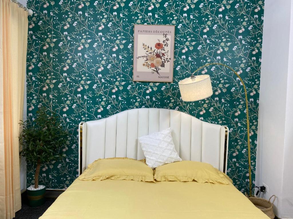 河内FlowerGod Apartments - BlackPink HomeStay的一间卧室配有一张带绿色和白色壁纸的床