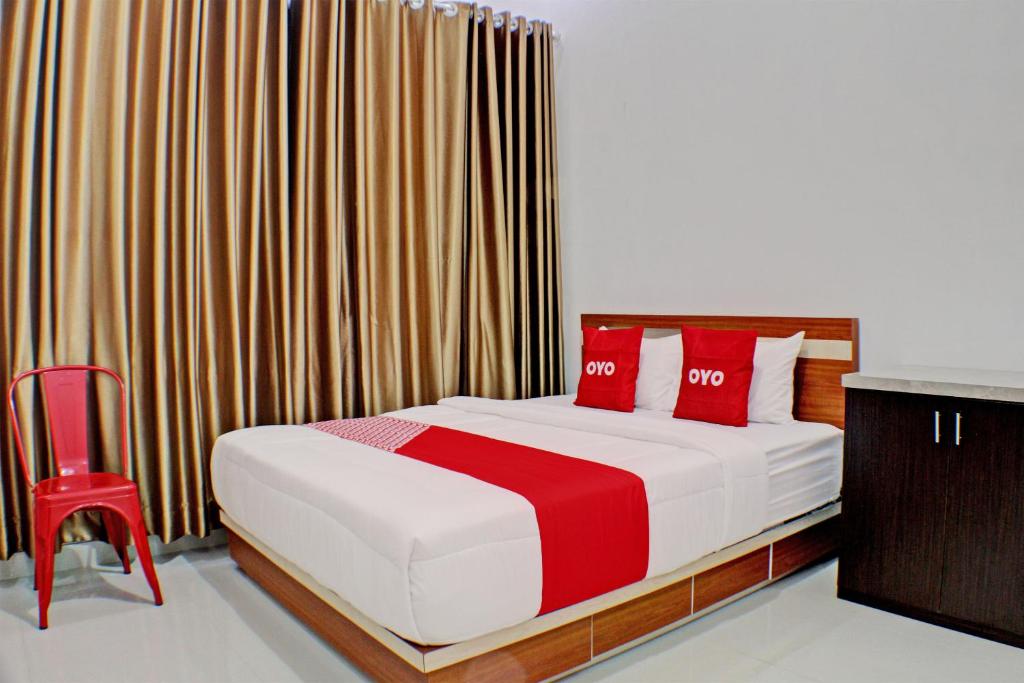 班达楠榜OYO 92945 Guest House Nusa Indah Syariah的一间卧室配有红色枕头和红色椅子。