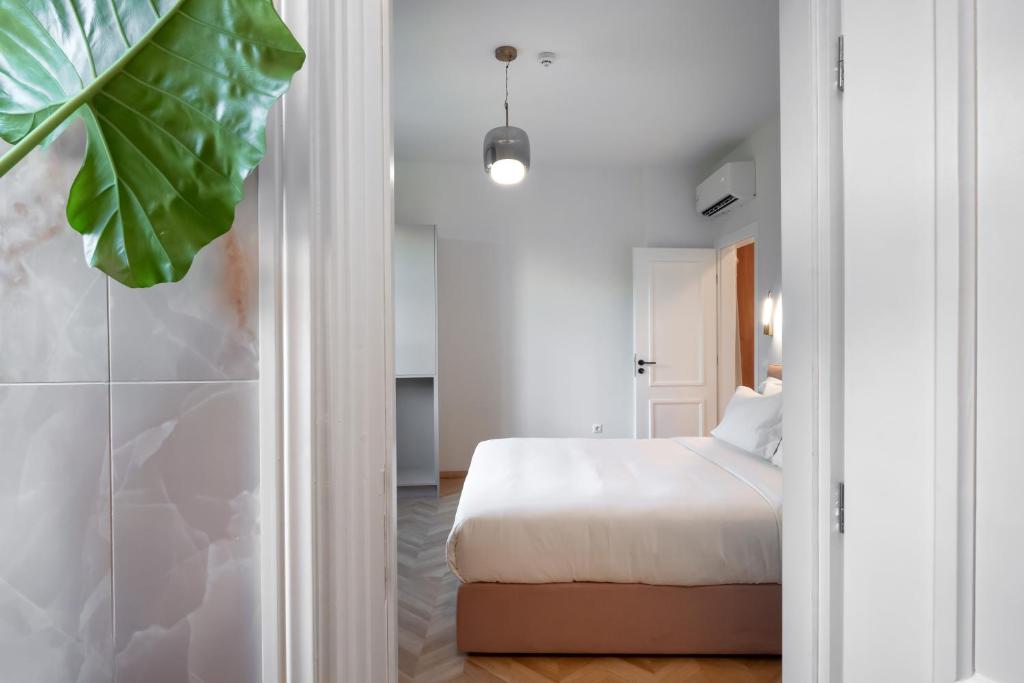 雅典The Aeolian的一间卧室设有床铺和大型绿色植物