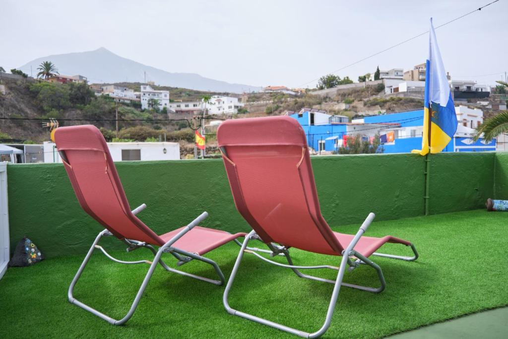 La GuanchaCuarto Verode Apartamento Santo Domingo的两把红色椅子坐在绿草上