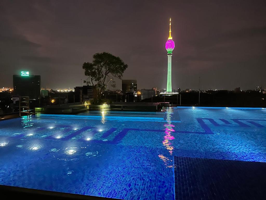 科伦坡Cosy home in heart of Colombo at Capitol Twinpeaks.的一座晚上设有电视塔的游泳池