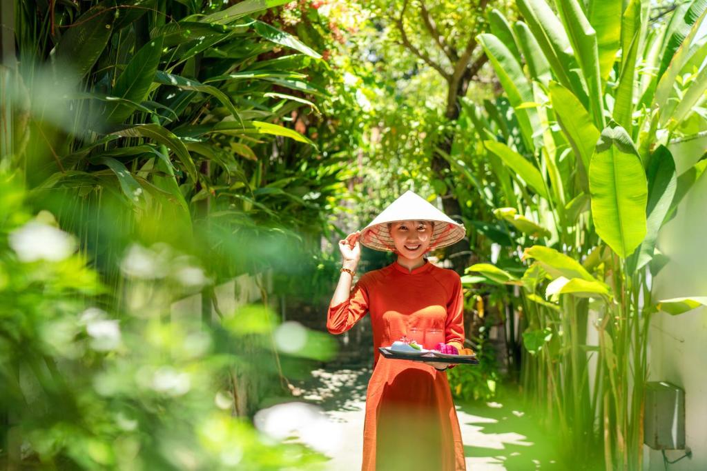 会安December Hoi An Villa的戴帽子的女人在森林中行走