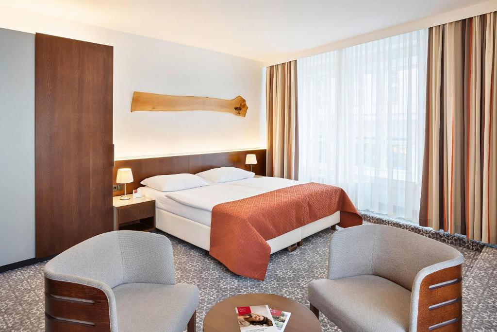 维也纳欧洲维也纳奥地利流行酒店的酒店客房,配有一张床和两把椅子