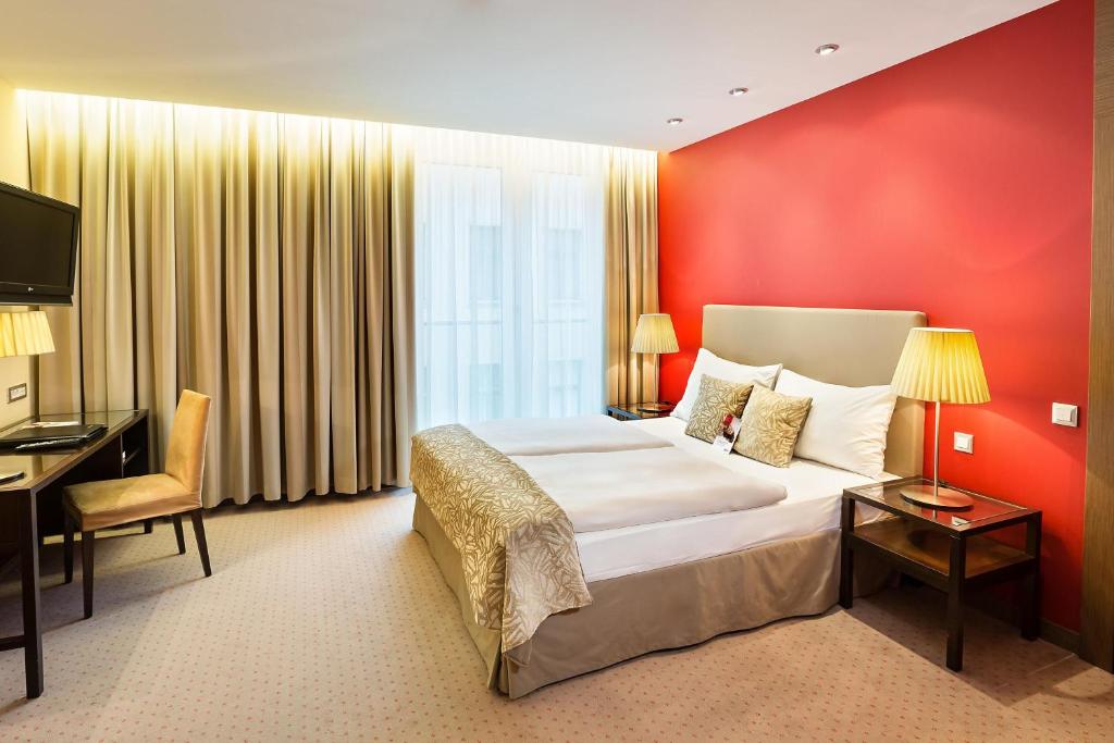 维也纳Austria Trend Hotel Savoyen Vienna - 4 stars superior的酒店客房设有一张大床和一张书桌。