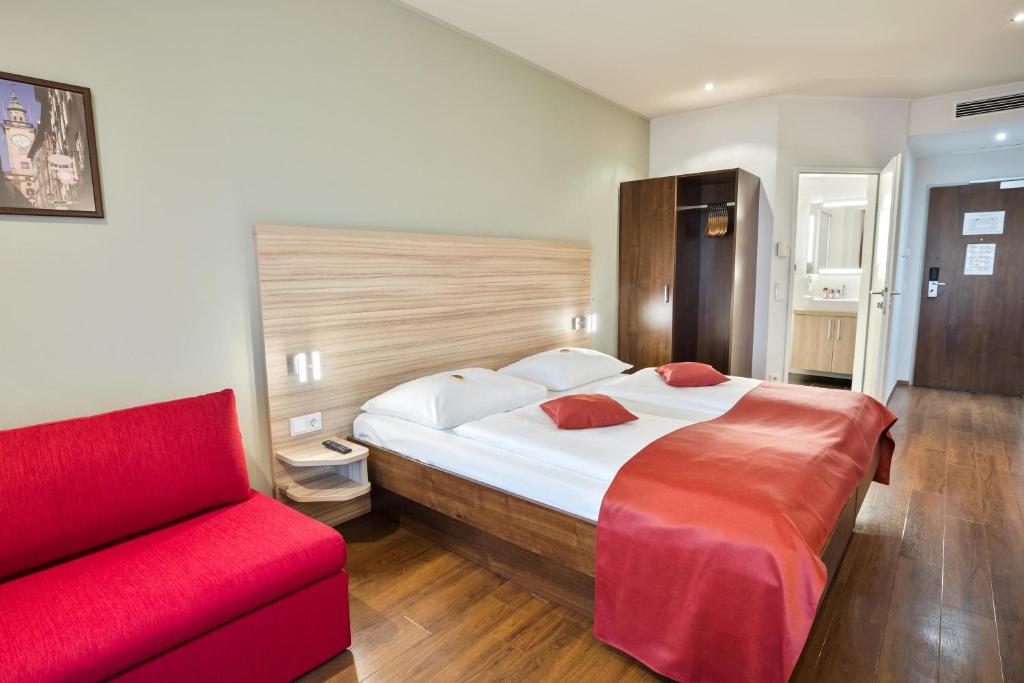 萨尔茨堡Austria Trend Hotel Salzburg Messe的一间卧室配有一张大床和一张红色的沙发