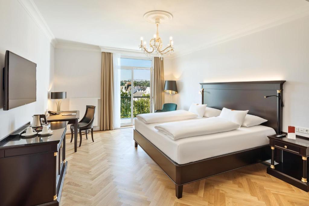 维也纳维也纳美泉宫奥地利时尚公园酒店的酒店客房配有一张床铺、一张桌子和一张书桌。