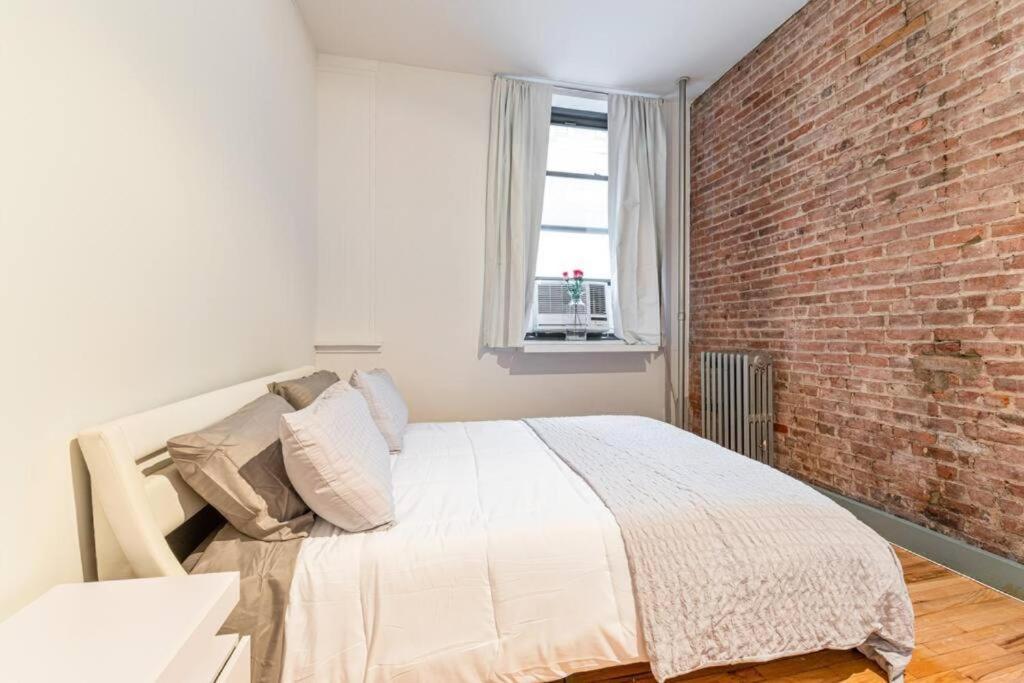 纽约4BR in the heart of Tribeca的一间卧室设有砖墙和一张床