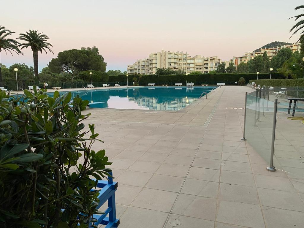曼德琉-拉纳普勒Studio Cannes Marina Mandelieu的一个带椅子的游泳池以及位于后面的建筑