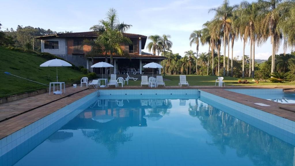 南蒙蒂阿莱格里Fazenda Água Clara的一个带椅子的游泳池以及一座棕榈树房子