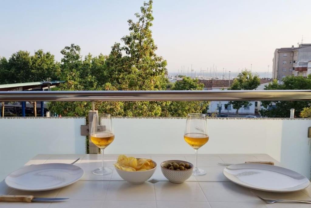 罗萨斯Piso en el centro con vistas al mar y balcón的一张桌子,上面放着两杯葡萄酒和一碗食物