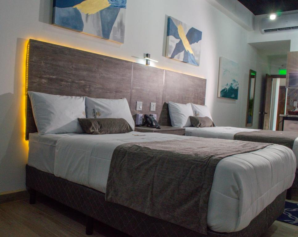 恩塞纳达港Hotel StayHome的一间卧室设有两张床和木制床头板