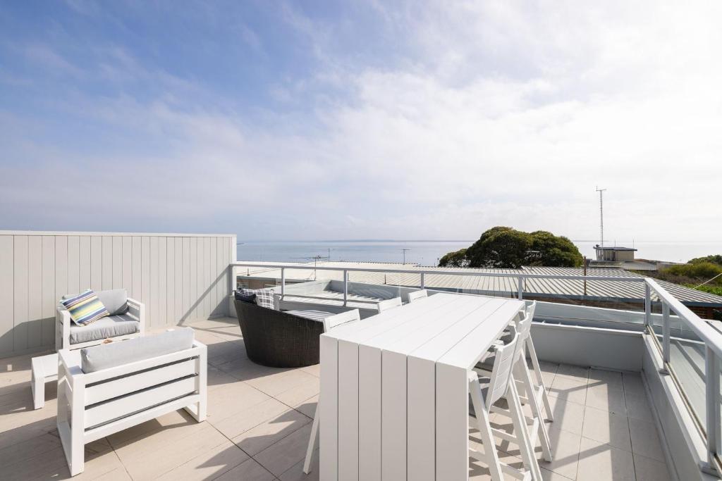 卡尔斯Hazelwood的阳台配有白色的桌椅,享有海景。