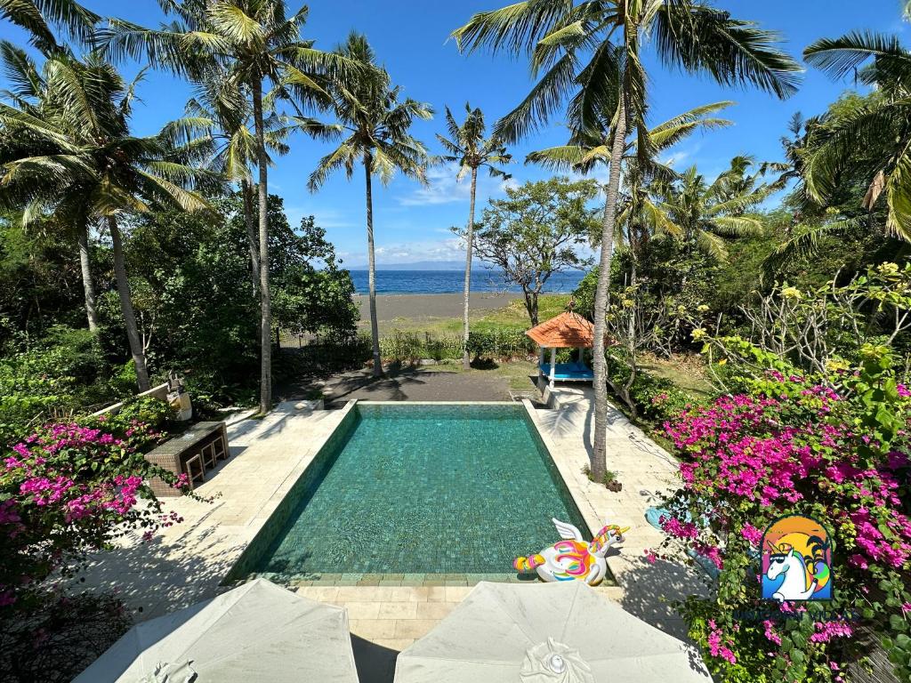 八丹拜Villa Black Pearl - by Unicorn Villas Bali的享有大海和棕榈树景致的游泳池