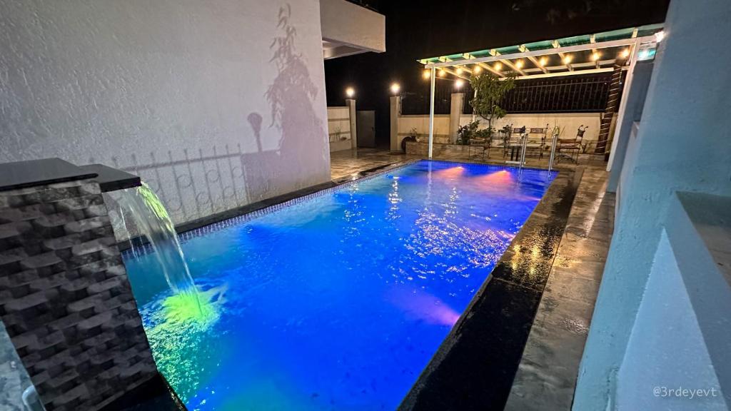 罗纳瓦拉Mystic Dreamville 3BHK Villa Lonavala的一个带瀑布和蓝色水的游泳池