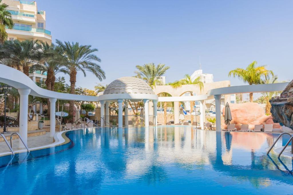 埃拉特YalaRent Golf Residence 3BR apt in luxury complex with pool的一个带椅子和树木的度假村游泳池