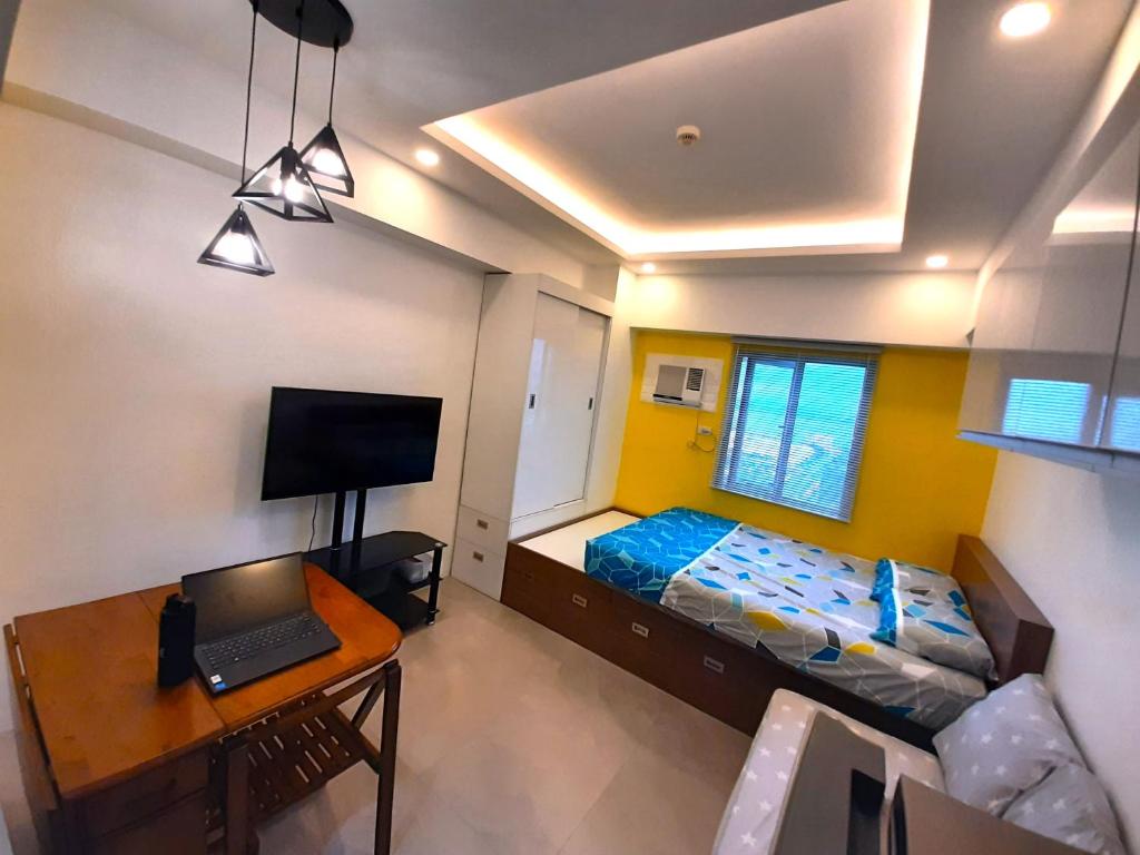 宿务1809 Sunvida Tower Condo across SM City Cebu的一间卧室配有一张床和一张带笔记本电脑的书桌