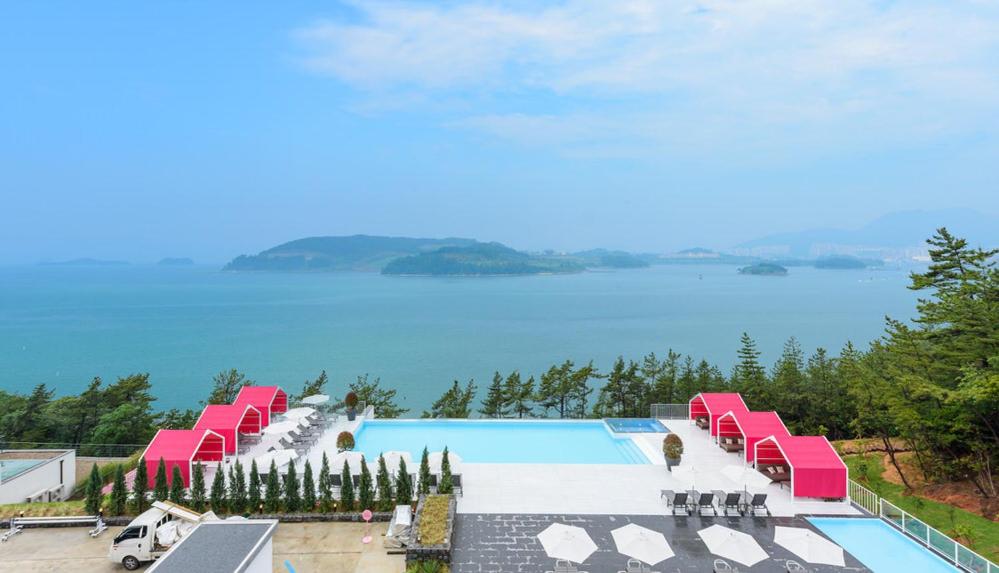 丽水市Vigo Resort的一个带粉红色椅子的游泳池,享有水景