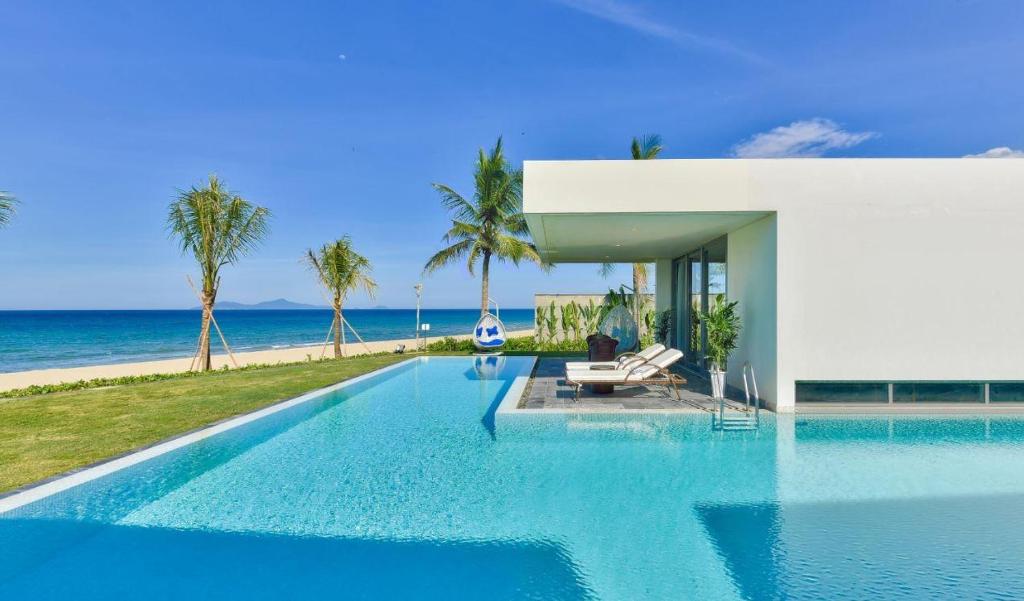 岘港Ocean Beach Villas Danang的一座位于大海房子前面的游泳池