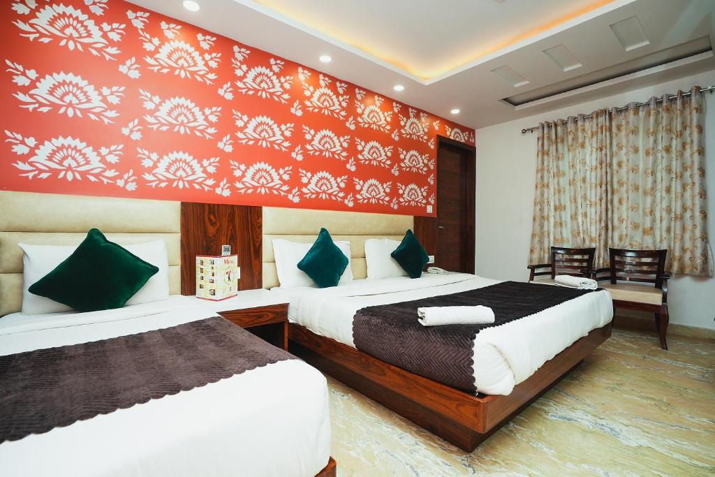新德里Hotel Kabir Palace Karol Bagh的一间卧室设有两张床和红色的墙壁