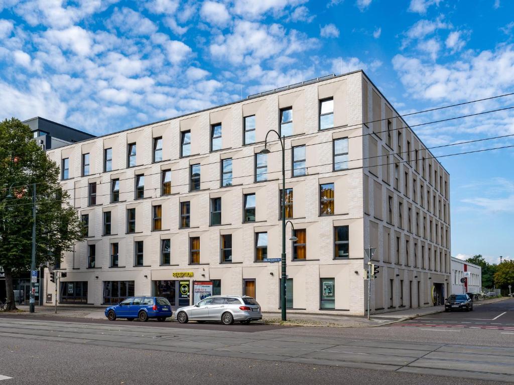 马格德堡B&B HOTEL Magdeburg-City的一座白色的建筑,前面有汽车停放