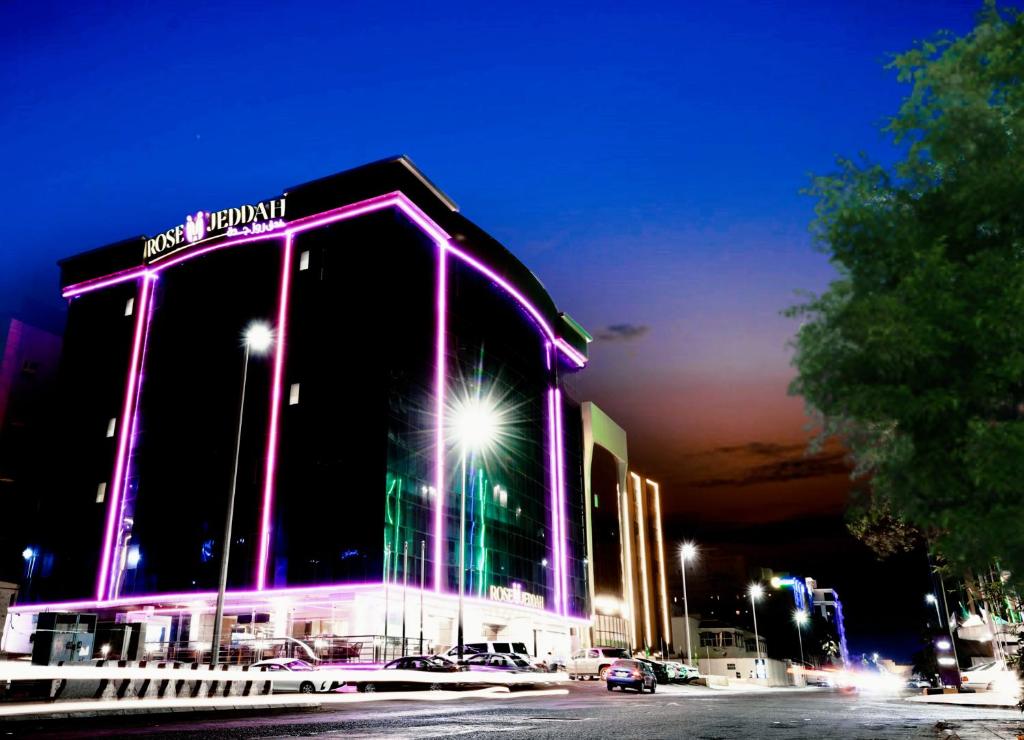 吉达Rose Jeddah Hotel的一座大建筑,晚上有紫色的灯光