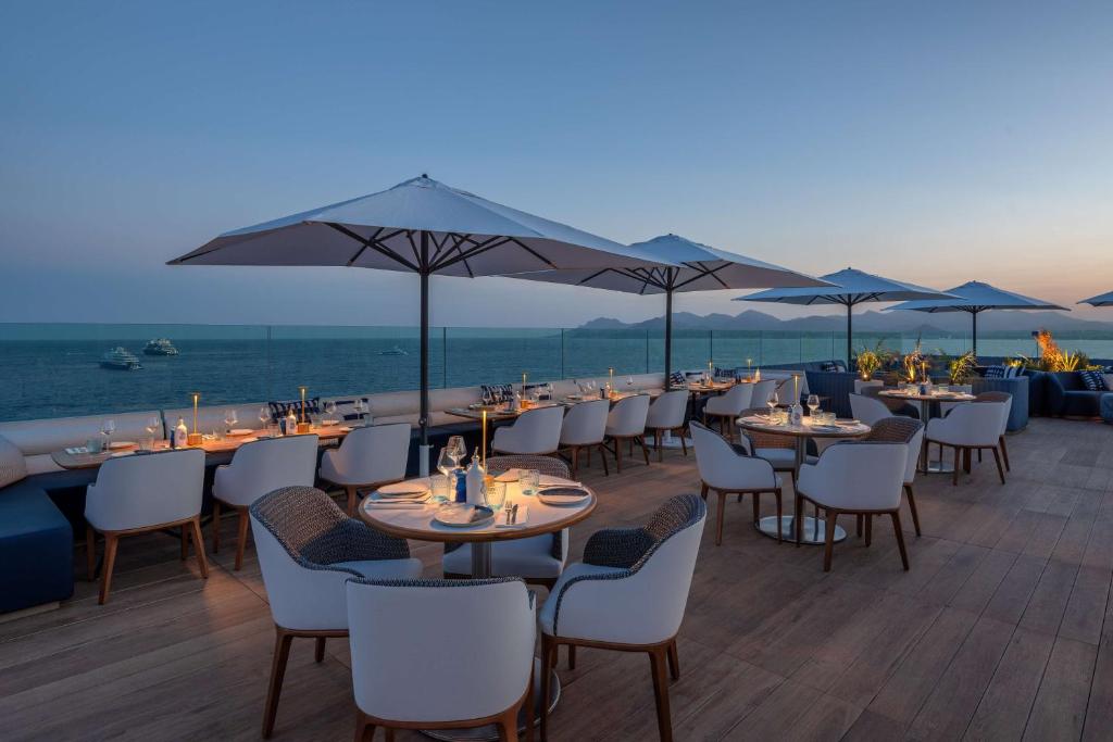 戛纳Canopy by Hilton Cannes的一间带桌椅的海景餐厅