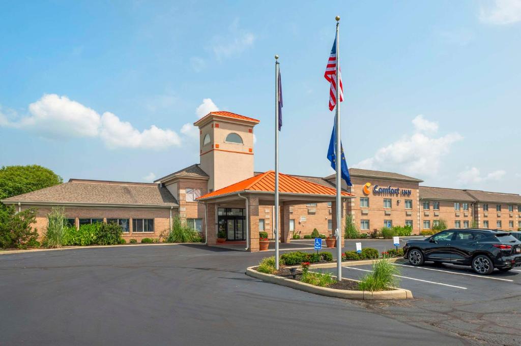 爱丁堡Comfort Inn Near Indiana Premium Outlets的停在有旗帜的建筑前面的汽车