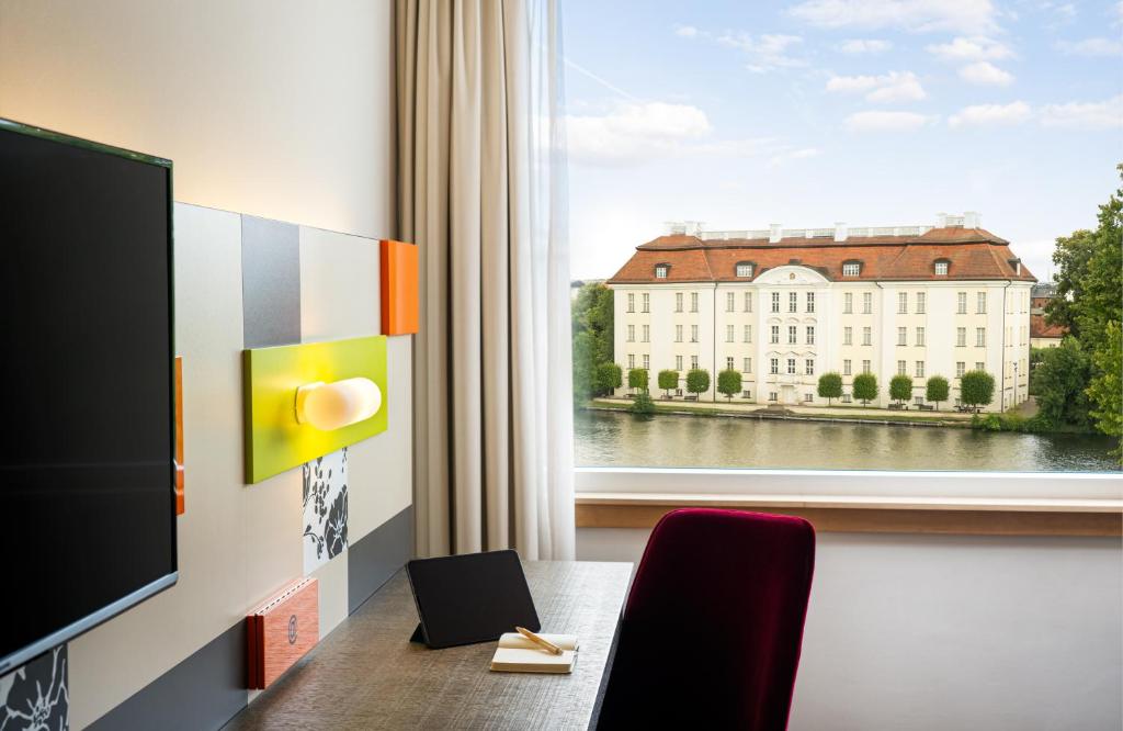 柏林HOTEL BERLIN KÖPENICK by Leonardo Hotels的一间设有桌子和窗户的客房,位于大楼内