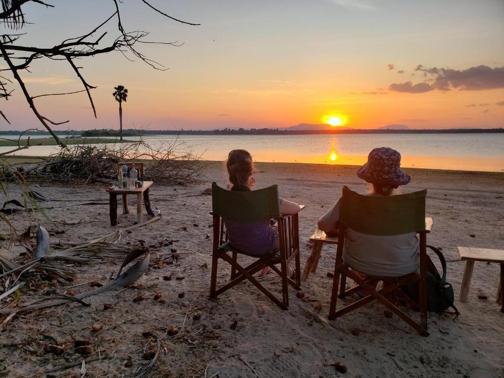 Kwa MhindaMakubi Safari Camp by Isyankisu的两人坐在沙滩椅上,欣赏日落