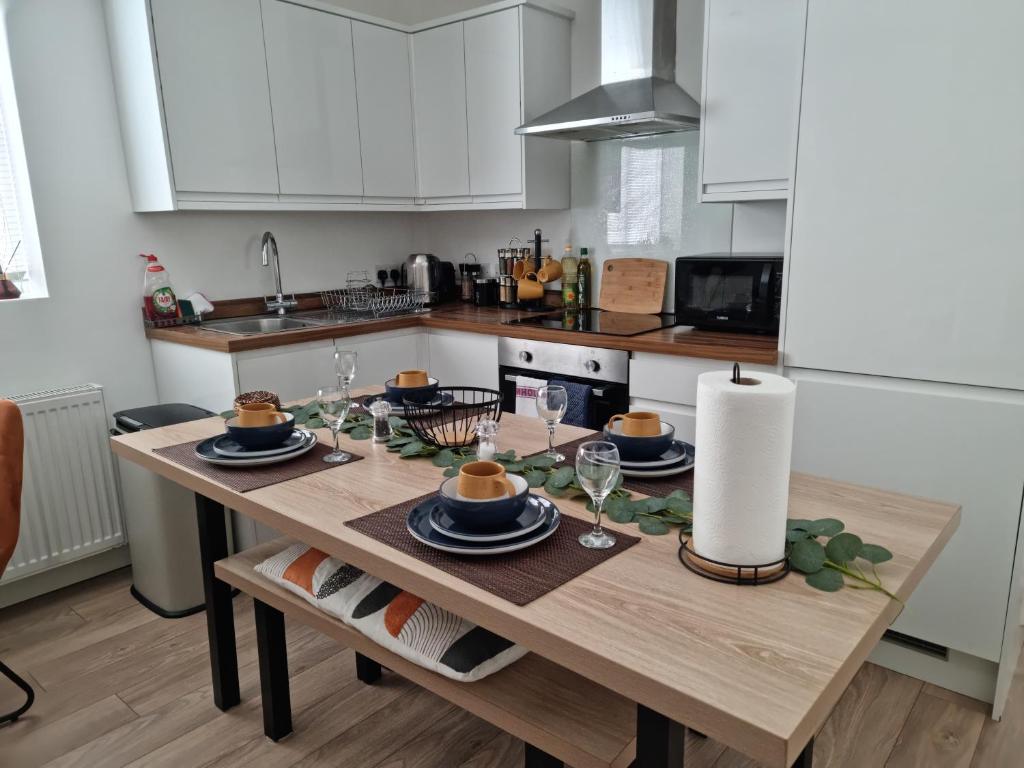沃特福德Central Watford Modern Apartment - Travellers & Contractors Welcomed的厨房配有木桌、盘子和酒杯