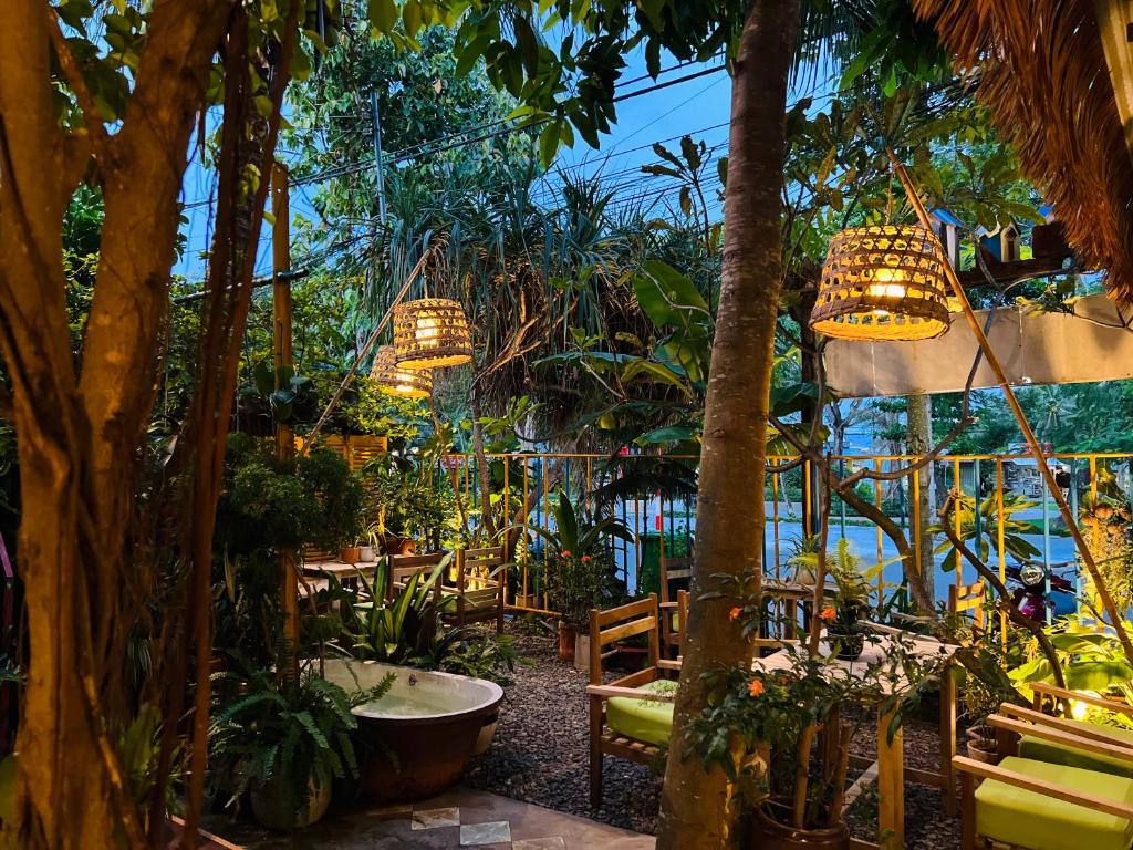 昆岛Uyen's House的花园内种有棕榈树、椅子和吊灯