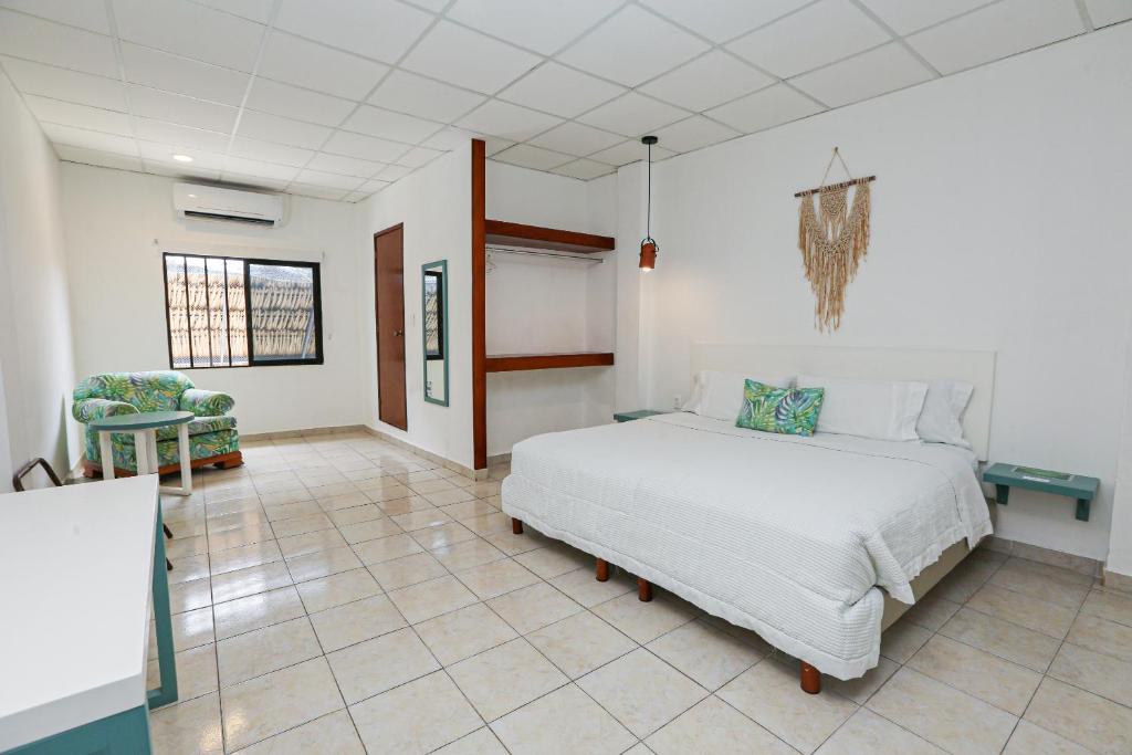 切图马尔Hotel & Suites Arges - Centro Chetumal的卧室配有白色的床,铺有瓷砖地板。