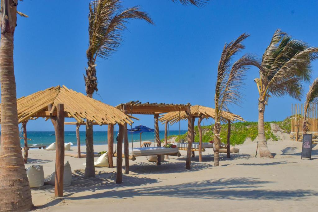 维加伊托Las Cabañas de Antica的沙滩上种有棕榈树和遮阳伞的海滩