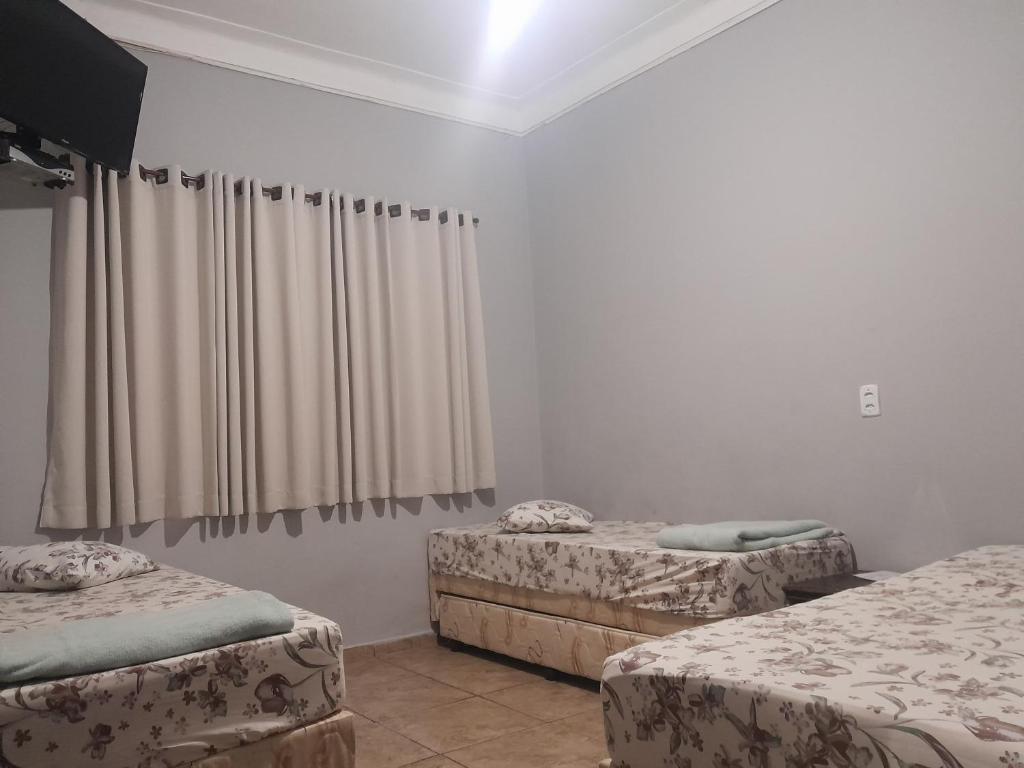 阿帕雷西达Pousada Vitória的客房设有两张单人床和窗帘