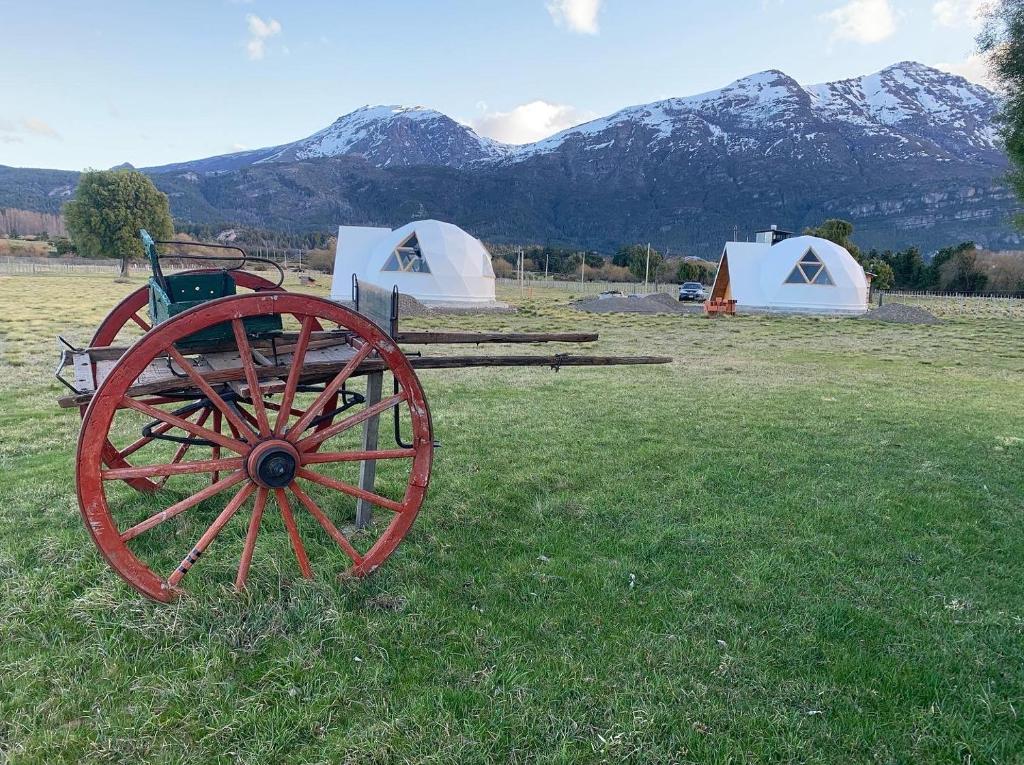 特来凡林Nomade Patagonia Glamping & Domos的一辆红色的马车,在田野里,有帐篷和山地