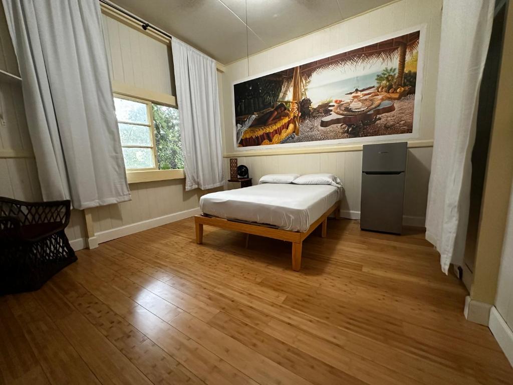 希洛Wild Ginger Hotel的卧室配有一张床,墙上挂有绘画作品
