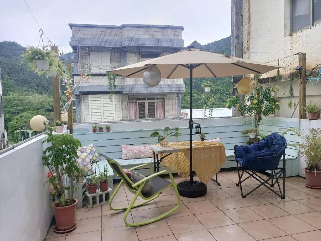 绿岛七十腳落背包客棧的庭院配有桌子、遮阳伞和椅子