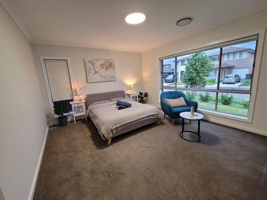Marsden Park5 bedroom new house (no stairs)的卧室配有床、椅子和窗户。
