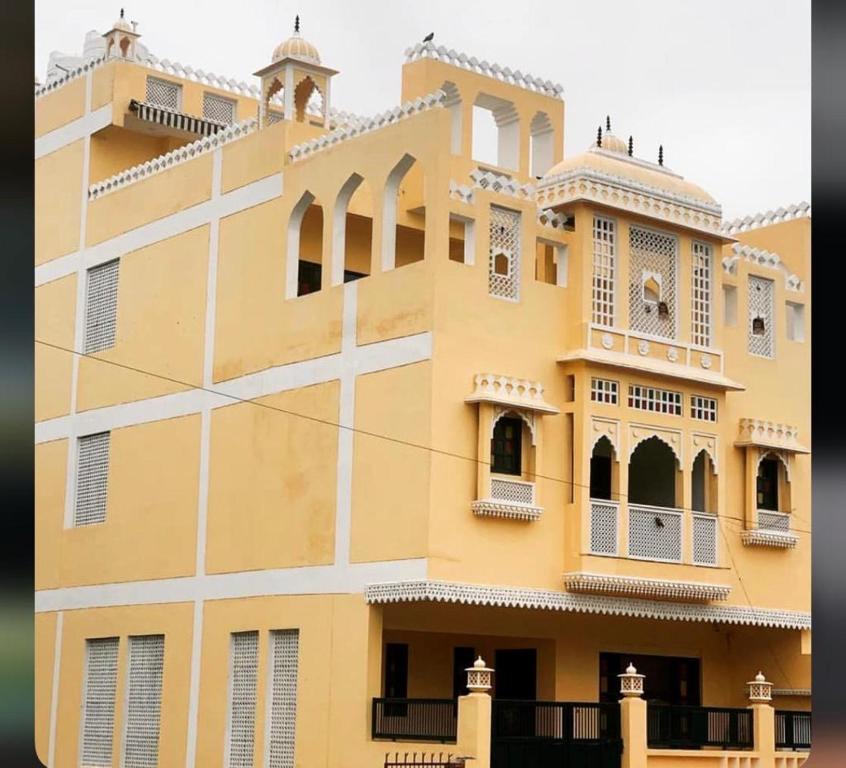 阿格拉Shiv Kothi - Homestay的大型黄色建筑,设有窗户和阳台